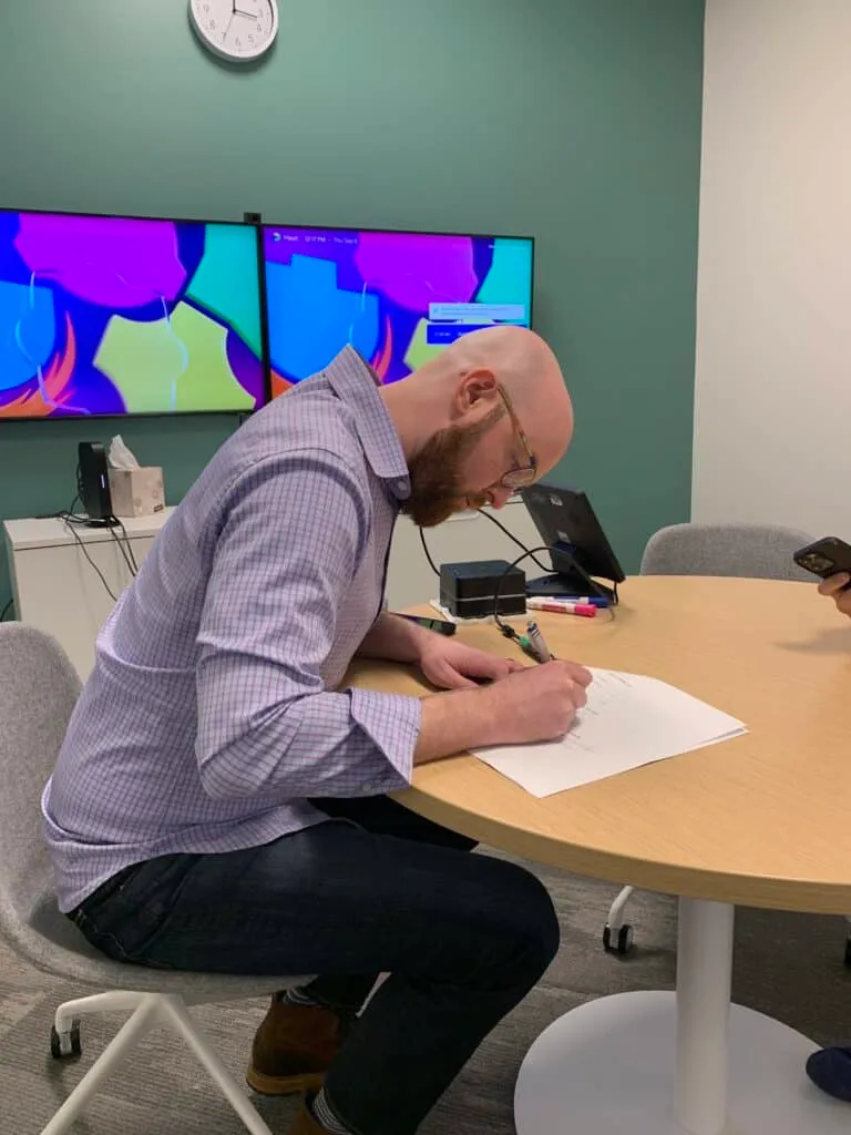 Signing a document at a table during the Traffic Think Tank sale process.