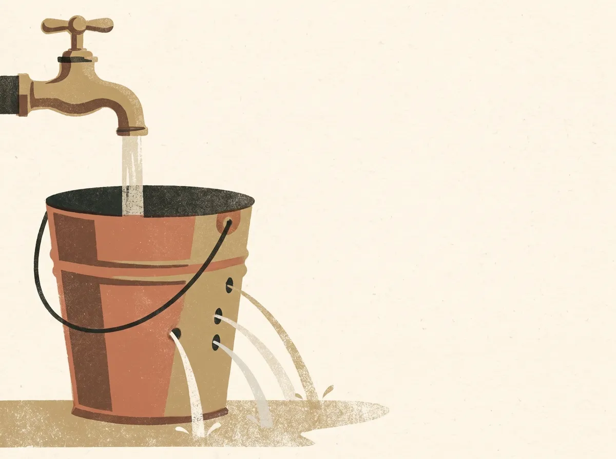 A bucket under a running tap, with water leaking out through four holes in its side into a puddle.